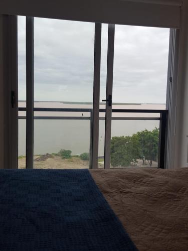 een slaapkamer met een bed en een groot raam bij Departamento sobre el Rio. in Corrientes