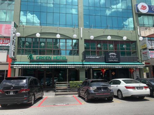 two cars parked in a parking lot in front of a building at Green Hotel in Puchong