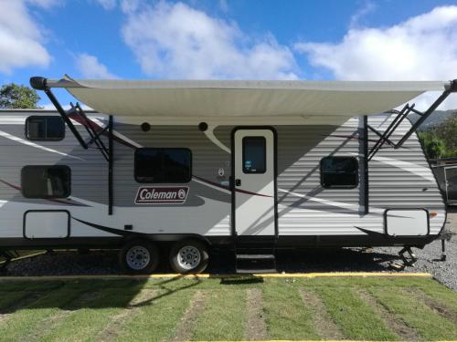 an rv with awning parked in a field at Panama Camping Park Boquete in Boquete