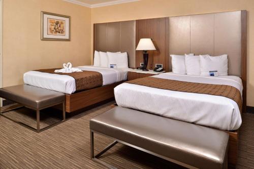 a hotel room with two beds and a table at Best Western Hollywood Plaza Inn - Hollywood Walk of Fame Hotel - LA in Los Angeles