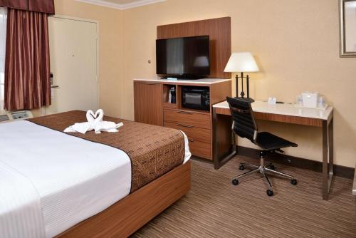 a hotel room with a bed and a desk with a computer at Best Western Hollywood Plaza Inn Hotel - Hollywood Walk of Fame LA in Los Angeles