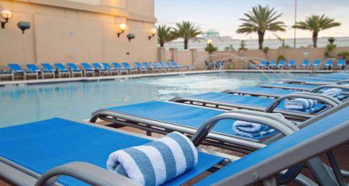 a pool with blue and white chairs and a swimming pool at The Florida Hotel & Conference Center in the Florida Mall in Orlando