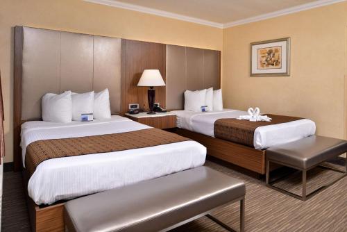 a hotel room with two beds and a chair at Best Western Hollywood Plaza Inn Hotel - Hollywood Walk of Fame LA in Los Angeles