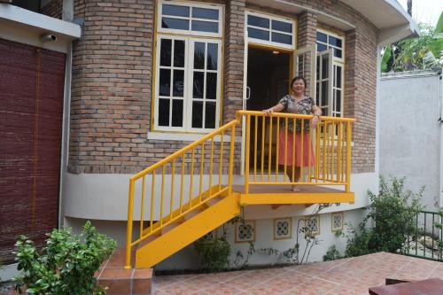 a woman standing on a yellow staircase outside a house at Hotel Deli River and Restaurant Omlandia in Medan