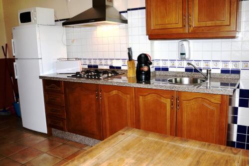 uma cozinha com armários de madeira e um frigorífico branco em Rural Apartments overlooking the Lake. em Ardales