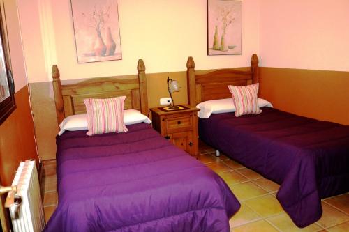 duas camas num quarto com lençóis roxos em Rural Apartments overlooking the Lake. em Ardales