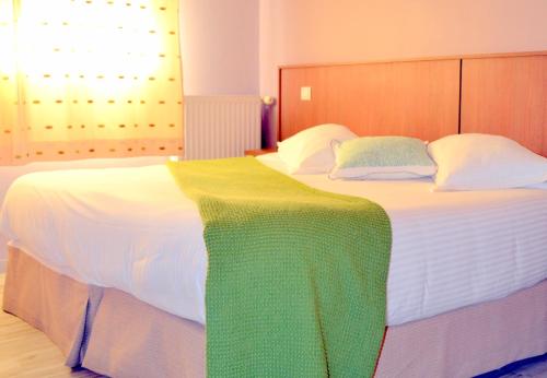 a large white bed with a colorful blanket on it at Le Rhien Hôtel-Restaurant in Ronchamp