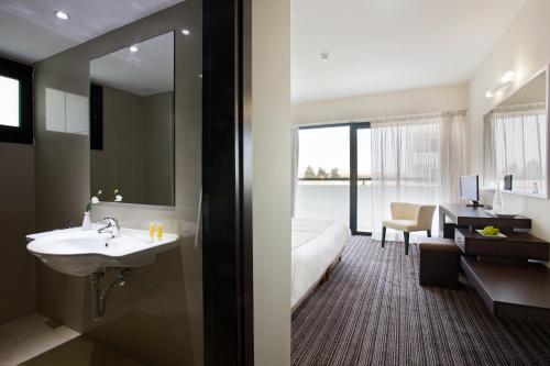 baño con lavabo, cama y espejo en Christofinia Hotel, en Ayia Napa
