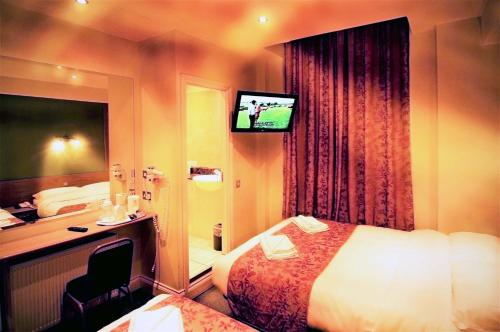 Habitación de hotel con cama y TV en Westbury Hotel Kensington, en Londres