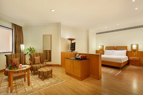 a hotel room with a bed and a table and chairs at Trident Chennai in Chennai