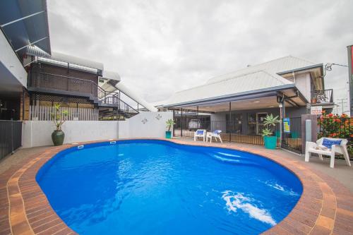 a large blue swimming pool in front of a house at Metro Motel Rockhampton in Rockhampton