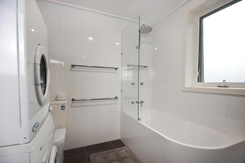 a white bathroom with a shower and a toilet at Maisonettes Falls Creek in Falls Creek