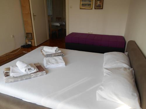 a white bed with towels on it with a purple couch at Dunavski Park in Novi Sad