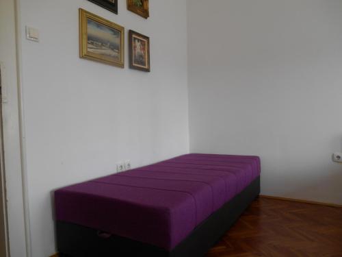 a purple bed in a white room with pictures on the wall at Dunavski Park in Novi Sad
