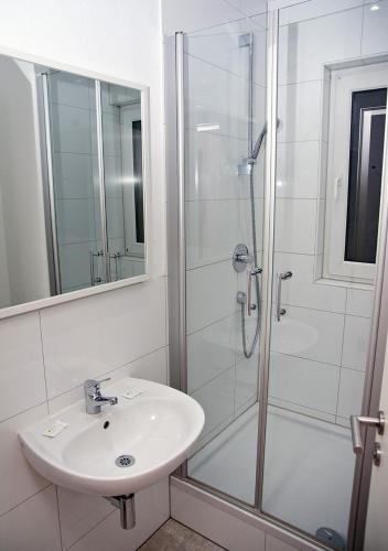 a white bathroom with a sink and a shower at Looks Inn in Heidelberg