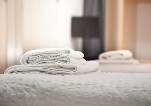 a stack of white towels sitting on a bed at Looks Inn in Heidelberg