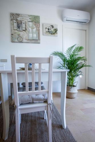 a white dining room table with a chair and a plant at Casali Marchigiani - Ville vacanza private con piscina in Ostra
