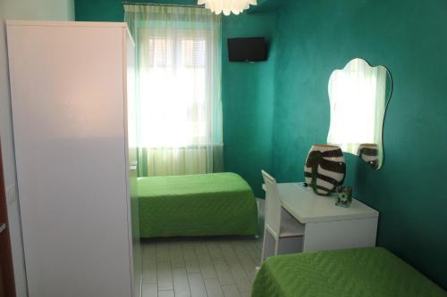 a green room with two beds and a chair at La Perla Del Conero Affittacamere in Numana