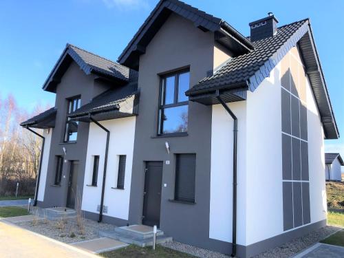 una casa bianca con tetto nero di Aqua Your Stay Apartamenty - Domy BartArt a Mielno