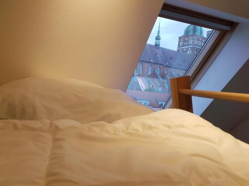 an unmade bed in a bedroom with a window at Rooftop Chalet in Stralsund
