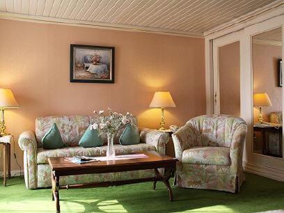 a living room with two couches and a table at Schwarzwaldhotel Stollen in Gutach im Breisgau