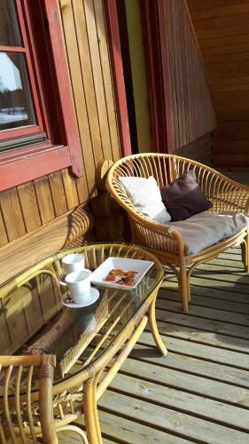 a porch with two wicker chairs and a table at Jaun-Ieviņas in Rauna