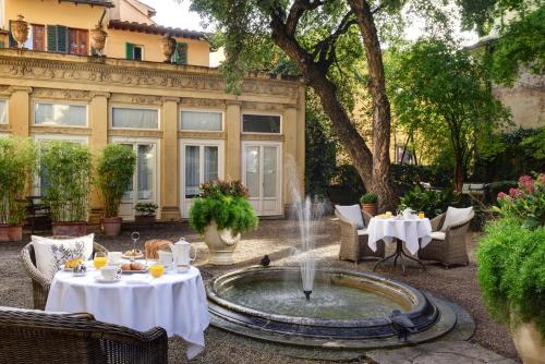 a fountain in the middle of a courtyard with tables at Al Palazzo del Marchese di Camugliano Residenza d'Epoca in Florence