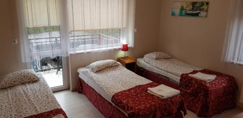 two twin beds in a room with a window at Pensjon Polska in Poznań