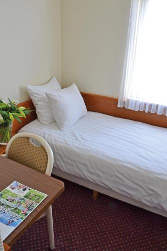 a hotel room with a bed and a table and a window at Fletcher Hotel De Zalm in Brielle