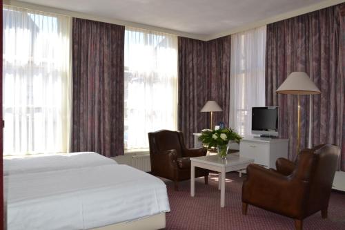 a hotel room with a bed and chairs and a tv at Fletcher Hotel De Zalm in Brielle