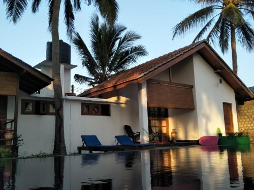 a house with a swimming pool and palm trees at Bella Nilaveli Beach in Nilaveli