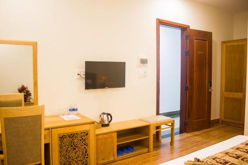 een kamer met een bureau en een tv aan de muur bij Hoài Thương Hotel in Pleiku