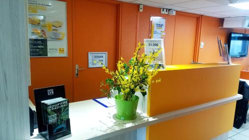 a counter with a vase of yellow flowers on it at Premiere Classe Périgueux - Boulazac in Boulazac