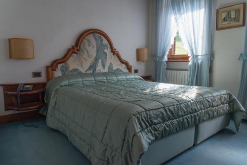 a bedroom with a large bed and a window at Hotel Alla Posta - Famiglia Pra dal 1866 a Caprile in Alleghe