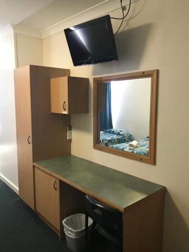 a room with a desk with a mirror and a tv at O'Shea's Royal Hotel in Goondiwindi