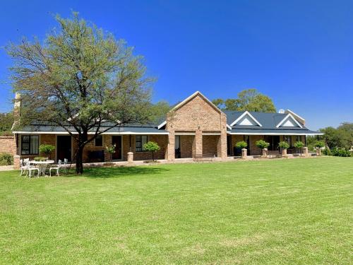 een groot huis met een grasveld ervoor bij 2 Owls Guesthouse in Potchefstroom