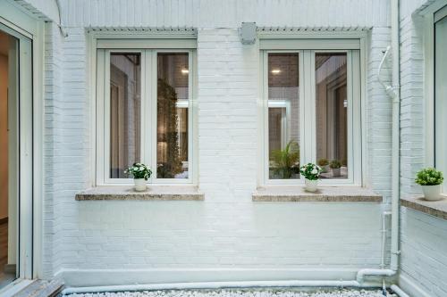 a white house with two windows and potted plants at Exclusive quietness in the heart of Madrid with Public Parking, Breakfast, 2 bathrooms in Madrid