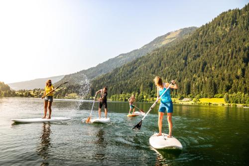 a group of people on paddle boards in the water at Familien- Sportresort BRENNSEEHOF in Feld am See