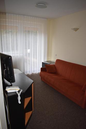 a living room with a couch and a television at Ośrodek Wypoczynkowy Ania Dźwirzyno in Dźwirzyno
