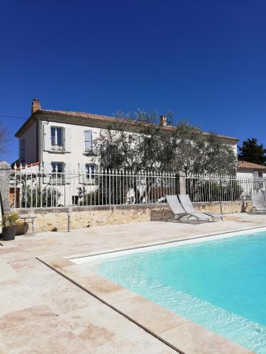a house and a swimming pool in front of a fence at Maison d'hôtes Le Jas Vieux in Montfort