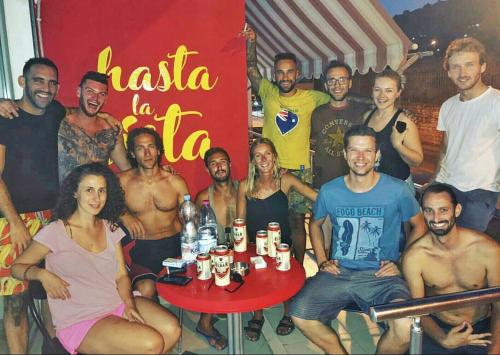a group of people sitting around a table with drinks at Hostel Hasta La Vista in Sarandë