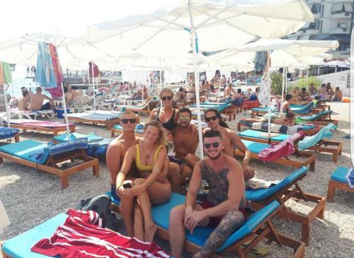 a group of people sitting on chaises at a beach at Hostel Hasta La Vista in Sarandë