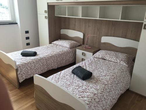 dwa łóżka w pokoju z dwoma czarnymi poduszkami w obiekcie VILLA DEGLI ULIVI w mieście Chiavari