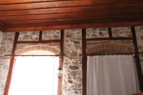 a room with a stone wall and a window with curtains at TAŞKONAK in Bergama
