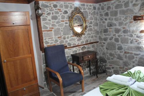a bedroom with a stone wall with a chair and a mirror at TAŞKONAK in Bergama