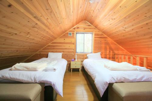 1 Schlafzimmer mit 2 Betten in einer Holzhütte in der Unterkunft るり渓 フォレストヴィラ in Nantan city