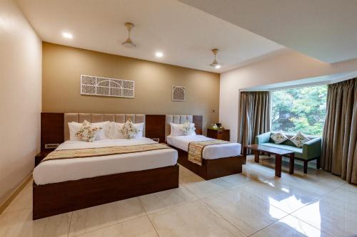Un dormitorio con dos camas y una silla y una ventana. en Mango Suites Viera, en Hyderabad