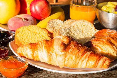 Un plato de pan y croissants en una mesa en The Originals Boutique, Hôtel Aquilon, Saint-Nazaire, en Saint-Nazaire
