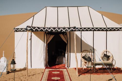 a tent in the desert with a chair in it at Desert Luxury Camp Erg Chigaga in El Gouera