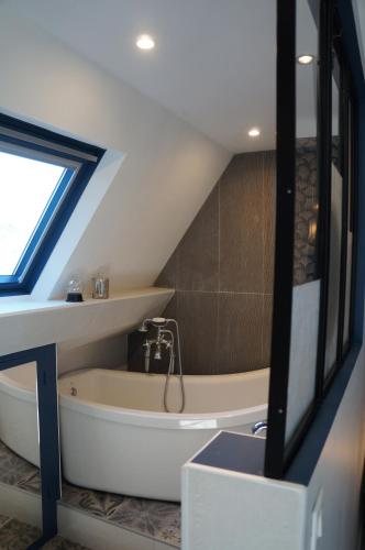 La salle de bains mansardée est pourvue d'une baignoire. dans l'établissement L'écrin de l'Océan, 80 mètres de la mer., au Pouliguen